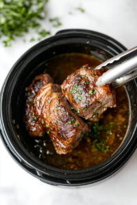This image shows the cooked pork loin being carefully removed from the slow cooker, ready for the final steps of resting and slicing.