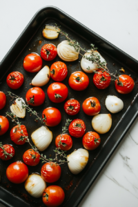 This image shows vegetables like cherry tomatoes and red onion being roasted on a sheet pan, ready for the Keto Sheet Pan Shrimp dish.