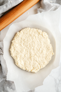 This image shows dough being rolled out on a floured surface with a rolling pin, creating the perfect thickness for the apple pie crust.