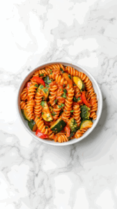 this image shows A steaming plate of 20-minute pasta with vegetables, topped with fresh herbs, ready to be served and enjoyed for a quick, satisfying meal.