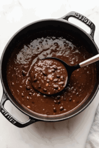 This image shows a steaming bowl of black bean soup served with a garnish of sliced avocado and fresh cilantro, creating a satisfying and colorful presentation.