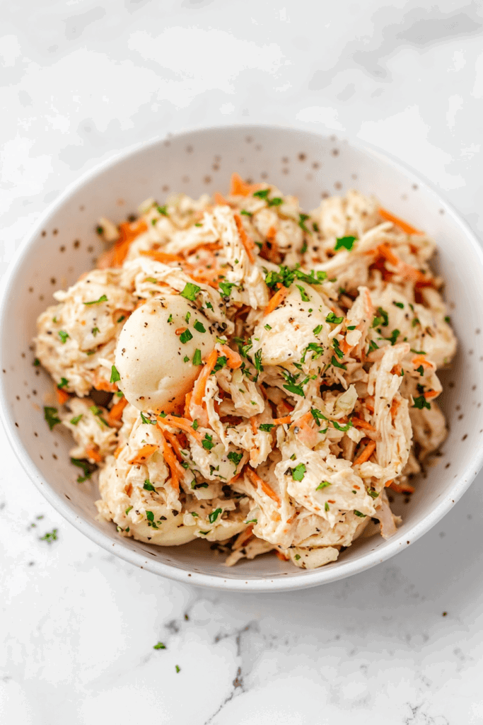 this image shows Tender shredded chicken sliders topped with crunchy shredded carrots and fresh cilantro, perfect for a casual meal.