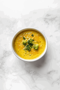 This image shows the blended vegan broccoli cheese soup simmering in a pot, ready to be served hot and garnished with fresh broccoli pieces.