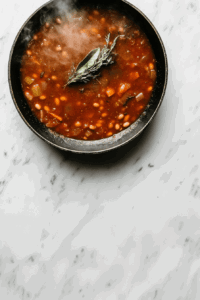 This image shows the vegetable and pinto bean soup simmering gently in a saucepan, allowing the flavors of potatoes, beans, and spices to meld together.