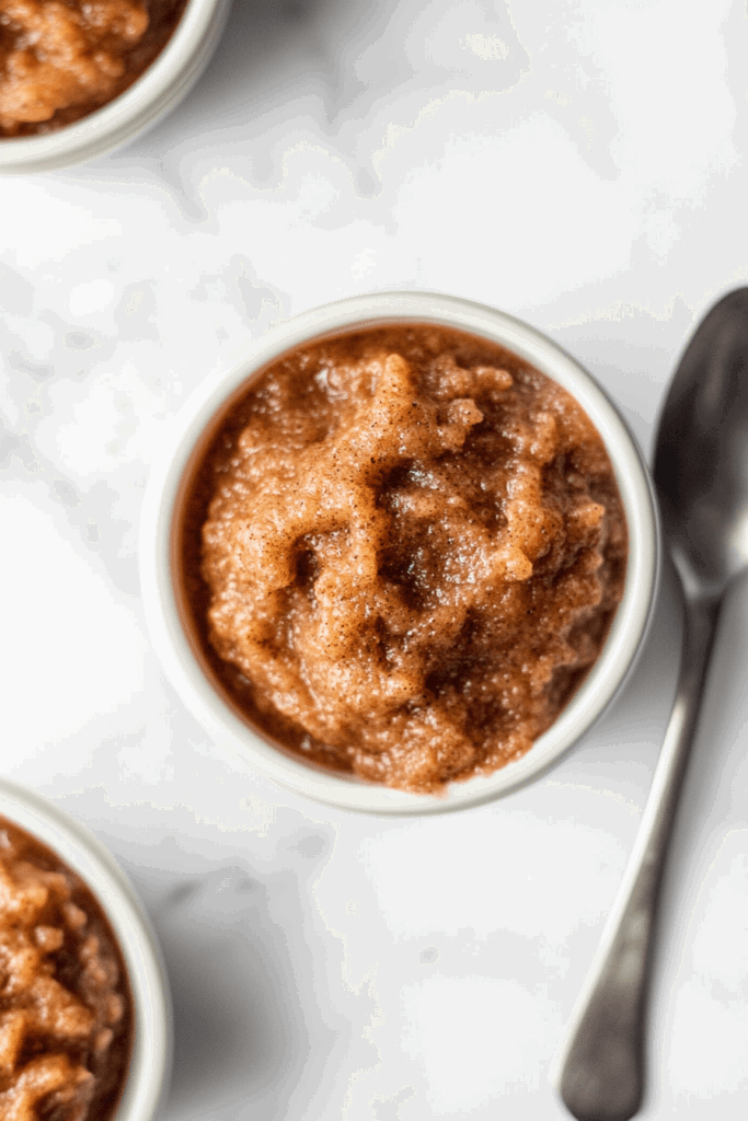 This image features slow-cooked apple butter, smooth and flavorful, served in a white bowl with a spoon on the side for easy serving.