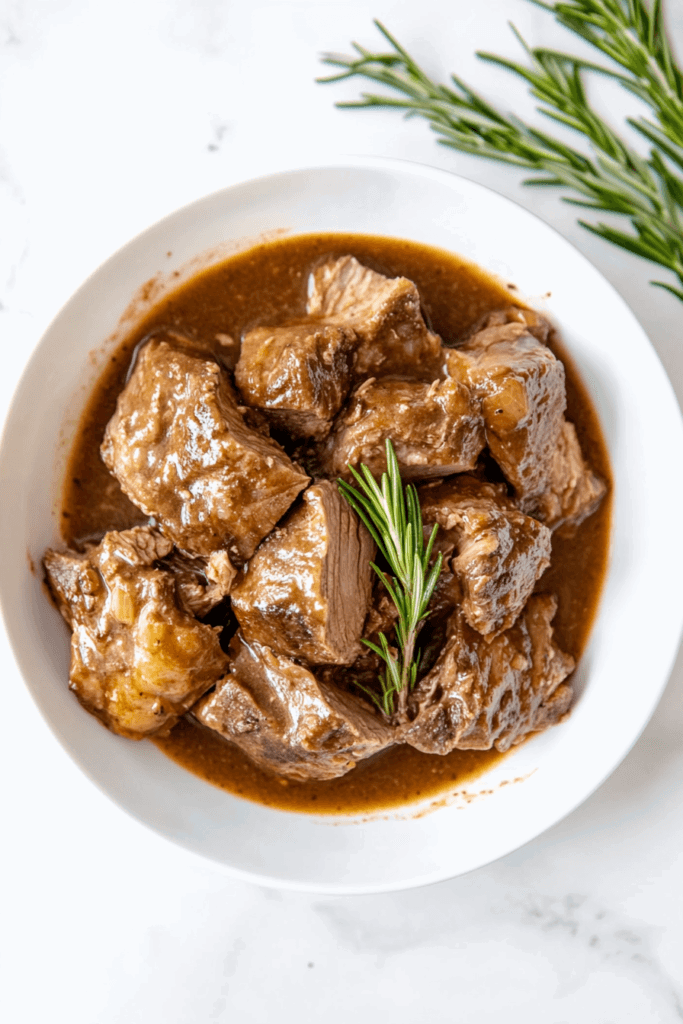 this image shows tender and juicy slow cooker pork loin, served in a savory broth and garnished with fragrant rosemary for a classic touch.