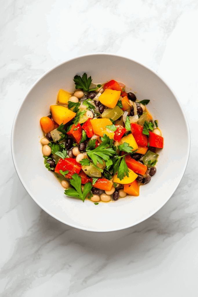 This image displays a wholesome slow-cooked vegetable and bean soup, featuring vibrant bell peppers, tomatoes, and fresh cilantro.