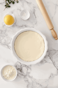 This image shows dough being pressed and spread evenly into a pie pan, creating the base for the vegan brownie pie before baking.