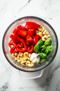 this image shows Cooked pasta being tossed in a skillet with the rich and creamy roasted red pepper cashew sauce, coating each strand evenly for a flavorful dish.