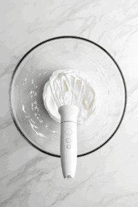 This image shows the whipped chickpea liquid achieving stiff peaks, a sign that it's ready to be transformed into creamy vegan whipped cream.