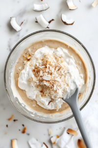 This image shows a mixing bowl with a hand mixer whipping coconut cream into a fluffy consistency with added vanilla and powdered sugar.