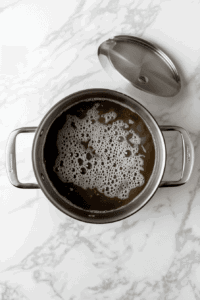 this image shows a steaming bowl of keto vegetable soup in a white ceramic bowl, filled with vibrant, tender vegetables like zucchini, spinach, cauliflower, and broccoli, all simmered in a savory broth