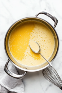This image shows a hand sprinkling salt, black pepper, and other seasonings into the broth to perfect the taste.