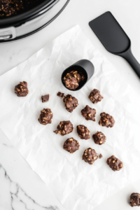 This image shows freshly formed peanut clusters resting on parchment paper, slowly setting into firm, bite-sized treats.