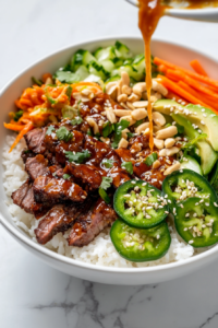 This image shows a beautifully assembled Vietnamese rice bowl with rice, caramelized meat, fresh cucumber herb salad, shredded carrots, avocado, sesame seeds, and pickled ginger, creating a visually stunning and delicious meal.
