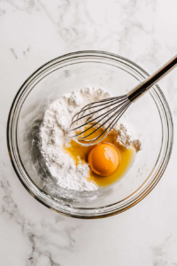 This image shows wet and dry ingredients being mixed to form a rich, smooth cake batter, ready for the next step.