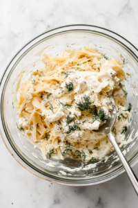 This image shows a spoon stirring the chicken and cheese mixture, ensuring all ingredients are well incorporated for a cohesive batter.