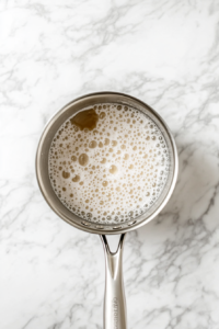 This image shows a saucepan of boiling syrup, bubbling intensely as it thickens to the perfect consistency for coating candy apples.