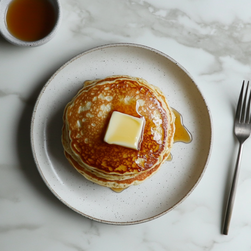 buttermilk-pancakes-with-melted-butter-and-maple-syrup-on-a-white-plate
