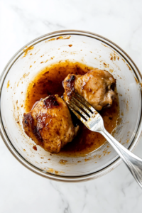 This image shows a top-down view of chicken pieces being coated evenly in a rich and flavorful marinade, ensuring a juicy and well-seasoned taste.