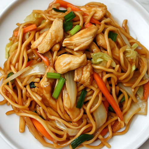 This image shows a plate of Chicken Spaghetti Lo Mein with tender chicken pieces and noodles tossed in a flavorful sauce made with soy sauce, oyster sauce, dark soy sauce, Shaoxing wine, and sesame oil.
