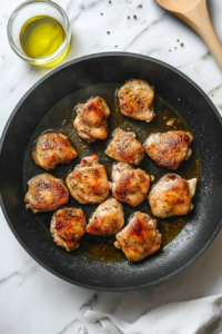 This image shows chicken being seasoned and browned in a pan, adding depth of flavor before baking.