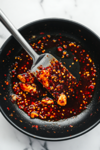 This image shows the crispy fried chicken being tossed in a thick, spicy sauce, ensuring every bite is packed with bold flavor.