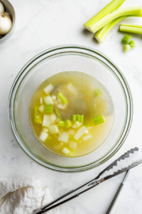 This image shows a mixing bowl filled with flour and other ingredients being stirred together to form a soft dumpling dough.