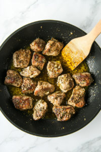 This image shows seasoned chicken pieces sizzling in a skillet, being cooked until golden brown and flavorful for the Broccoli Chicken Penne Pasta.