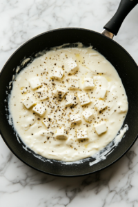 This image shows cubes of cream cheese slowly melting into the sauce, creating a rich, velvety texture with bold ranch flavor.