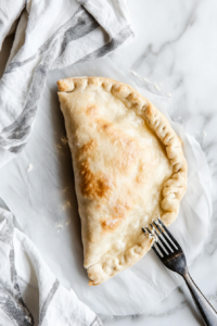 This image shows calzones cooking inside an air fryer, turning golden brown and crispy on the outside while the filling becomes hot and melty.