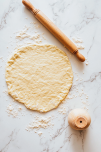 This image shows a sharp knife slicing the rolled-out dumpling dough into evenly sized strips, ready for cooking.