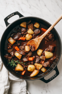This image shows a wooden spoon scraping up the flavorful browned bits from the bottom of a pot, ensuring that all the delicious caramelized flavors are incorporated into the chicken vegetable stew.