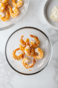 This image shows fresh shrimp being coated in a light, airy batter to create a crispy golden crust when fried.
