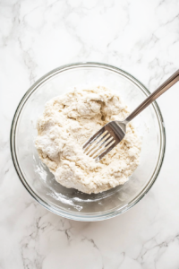 This image shows dumpling dough coming together in a bowl, creating a smooth and pliable texture for rolling.