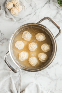 This image shows dumplings floating and cooking in the thickened broth, absorbing the rich flavors of the dish.