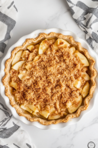 evenly-spreading-the-oat-and-brown-sugar-crumble-over-apples-in-a-baking-dish