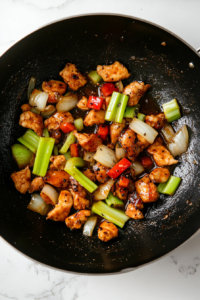 This image shows the completed Black Pepper Chicken stir-fry, with glazed chicken, cooked vegetables, and a rich sauce, ready to be served on a plate.