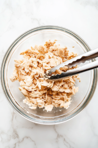 This image shows flaked whitefish meat being placed in a bowl and inspected for any remaining bones or skin.