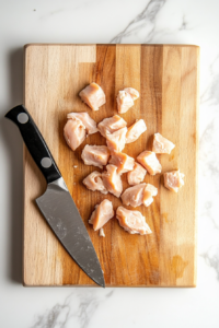 This image shows raw chicken being diced into small, uniform pieces, ensuring even cooking and a perfect fritter texture.