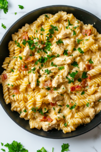 This image shows a final sprinkle of chopped cilantro over the chicken bacon ranch pasta, adding a fresh, herby contrast to the rich, creamy dish.