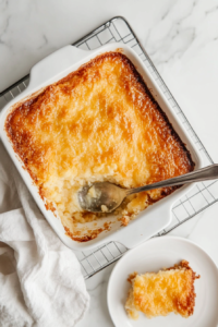 This image shows the Four-Ingredient Cheese Dump Cake cooling on a countertop, ready to be scooped and served warm.