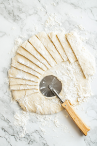 This image shows homemade dumpling strips resting on a surface, allowing them to set before being added to the broth.