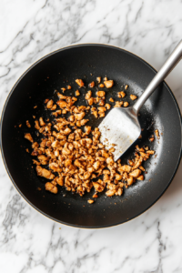 This image shows chicken pieces sizzling in a pan, turning golden brown and crispy as they cook.