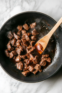 This image shows a vibrant addition of pickled ginger being placed on top of a Vietnamese rice bowl, adding a tangy and slightly spicy contrast to the dish.