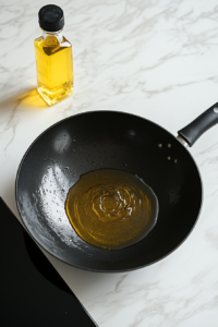 This image shows oil heating in a pan, preparing to cook the marinated chicken and vegetables for the Black Pepper Chicken stir-fry.