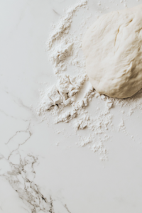 This image shows hands kneading the dough on a floured surface, developing the gluten for a soft and chewy texture.