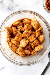 This image shows chicken pieces being marinated with seasoning and sauce, allowing the flavors to infuse for the Black Pepper Chicken dish.