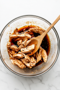 this image shows chicken being marinated in a bowl with sauces for chicken to soak in the flavors properly