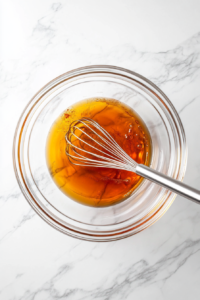 This image shows butter melting in a pan as hot sauce is poured in, creating a rich and spicy Buffalo sauce for coating the chicken wings.